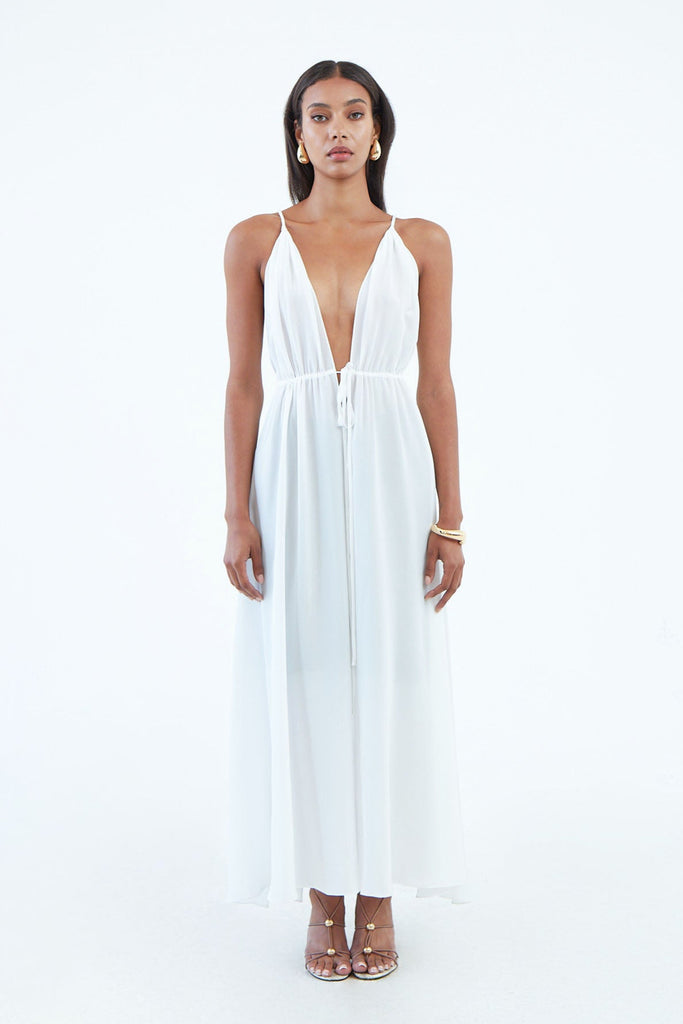 long white silk dress with thin shoulder straps, and full length front slit secured by waist tie.