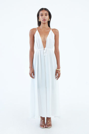 long white silk dress with thin shoulder straps, and full length front slit secured by waist tie.