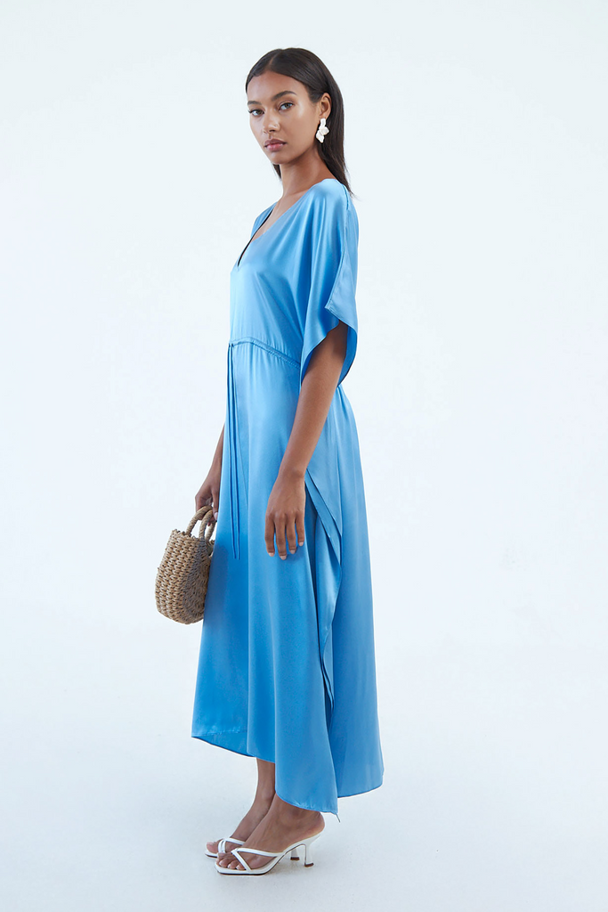 side view of full blue indigo blue silk kaftan dress with elastic waist tie, and wide elbow-length sleeves, continuous to hem
