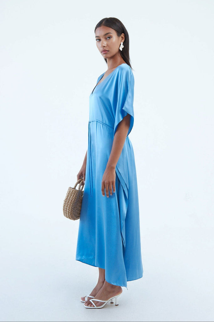 side view of full blue indigo blue silk kaftan dress with elastic waist tie, and wide elbow-length sleeves, continuous to hem