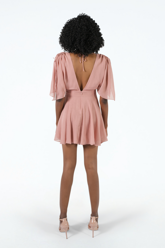 Back of pink silk crinkle short dress, fitted at waist, flared hem, open V back with back strap, ruffle sleeves, worn with pink heels 
