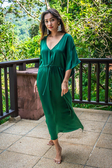 long emerald green silk kaftan dress with wide draped elbow-length sleeves, waist tie, and  low V neck