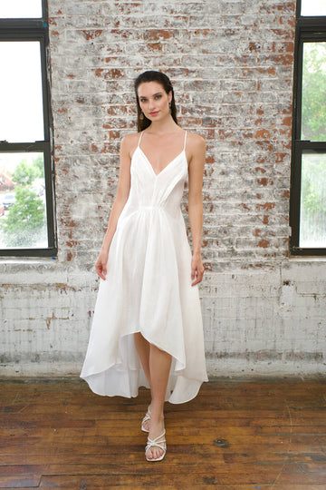 white hemp silk dress with thin shoulder straps, waist gather, and short front, long back flare, worn with white sandals