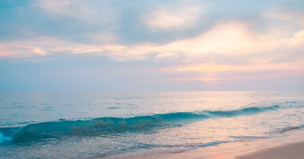 calm ocean with gentle waves, lavender, pink and orange sky