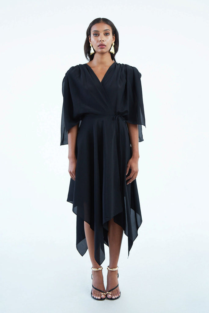 black silk wrap dress with wide sleeves, waist tie, and asymmetrical hem, worn with strappy heels
