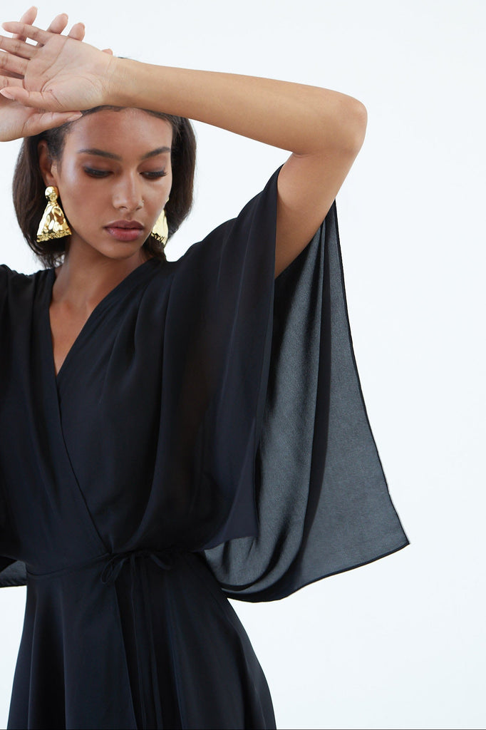 black silk wrap dress with wide sleeves, waist tie, and asymmetrical hem. 