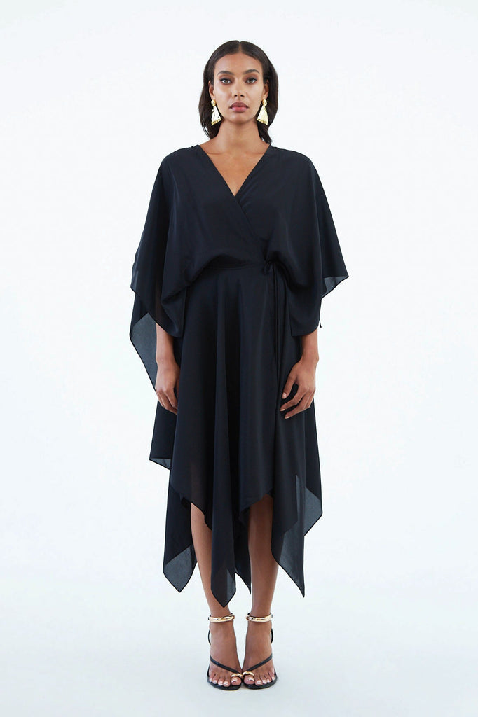 black silk wrap dress with wide sleeves, waist tie, and asymmetrical hem, worn with strappy heels