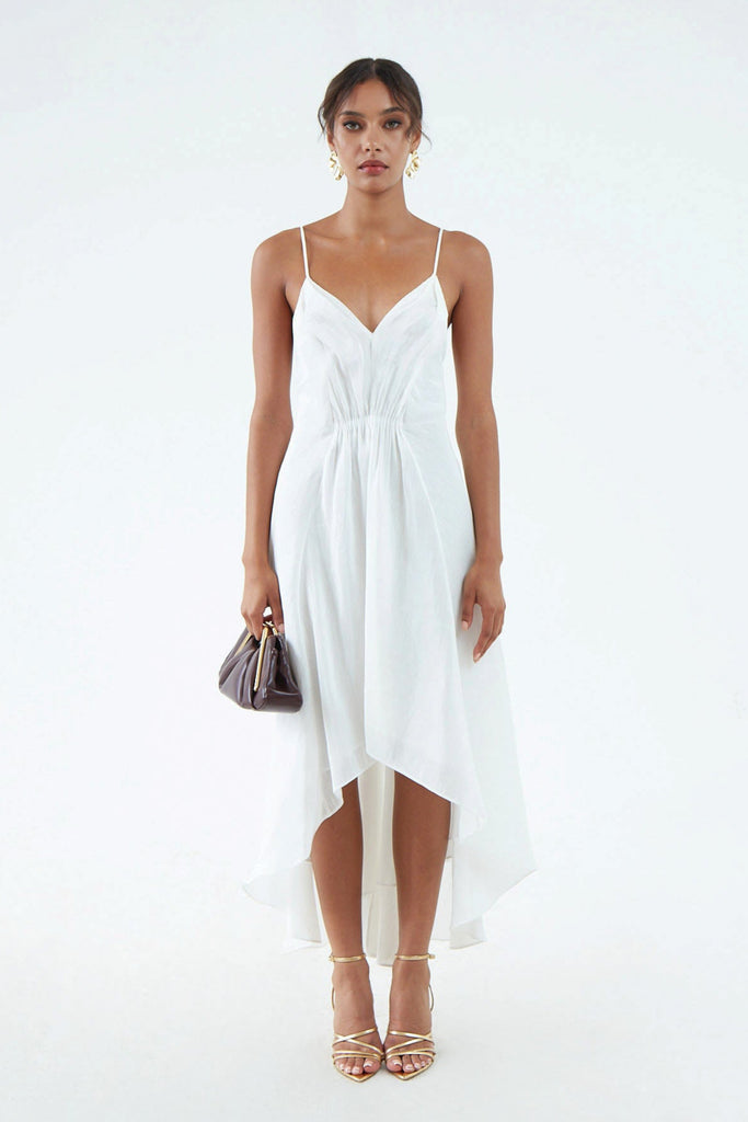 luxurious white hemp silk dress with thin shoulder straps, waist gather, flared hem that is short in front and long in back, worn with white sandals