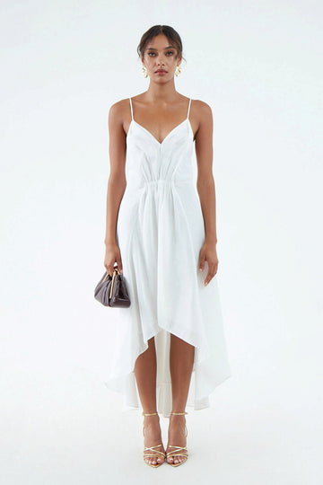 luxurious white hemp silk dress with thin shoulder straps, waist gather, flared hem that is short in front and long in back, worn with white sandals