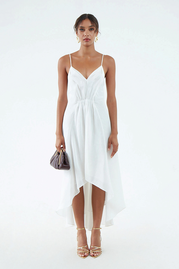 luxurious white hemp silk dress with thin shoulder straps, waist gather, flared hem that is short in front and long in back, worn with white sandals